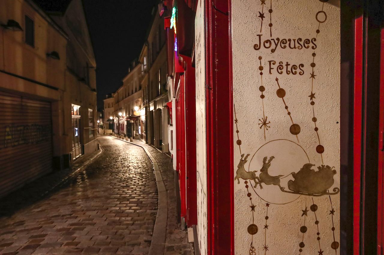A sign reading 'Happy Holidays' is pictured in an empty street during the new imposed curfew in Paris, Dec 15. Photo: AP