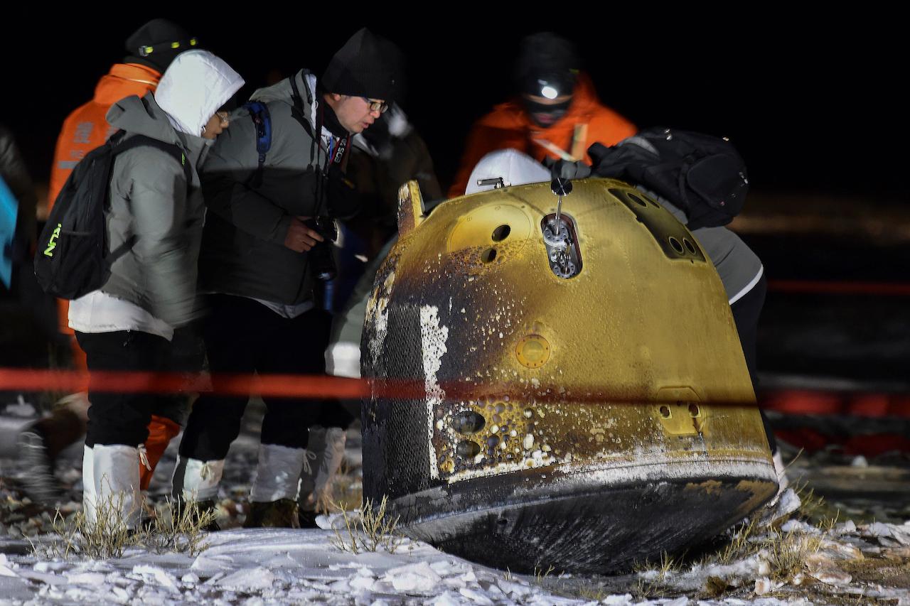 Recovery crew members check on the capsule of the Chang'e 5 probe after its successful landed in Siziwang district, north China's Inner Mongolia, Dec 17. Photo: AP
