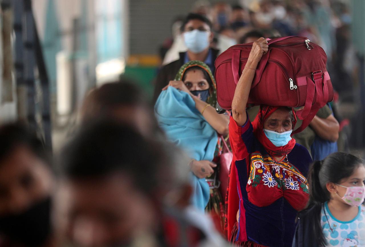 Passengers wearing masks wait in a queue for a body temperature check at Bandra train station in Mumbai, India, Dec 19. India's virus cases have crossed 10 million with new infections dipping to their lowest levels in three months. Photo: AP