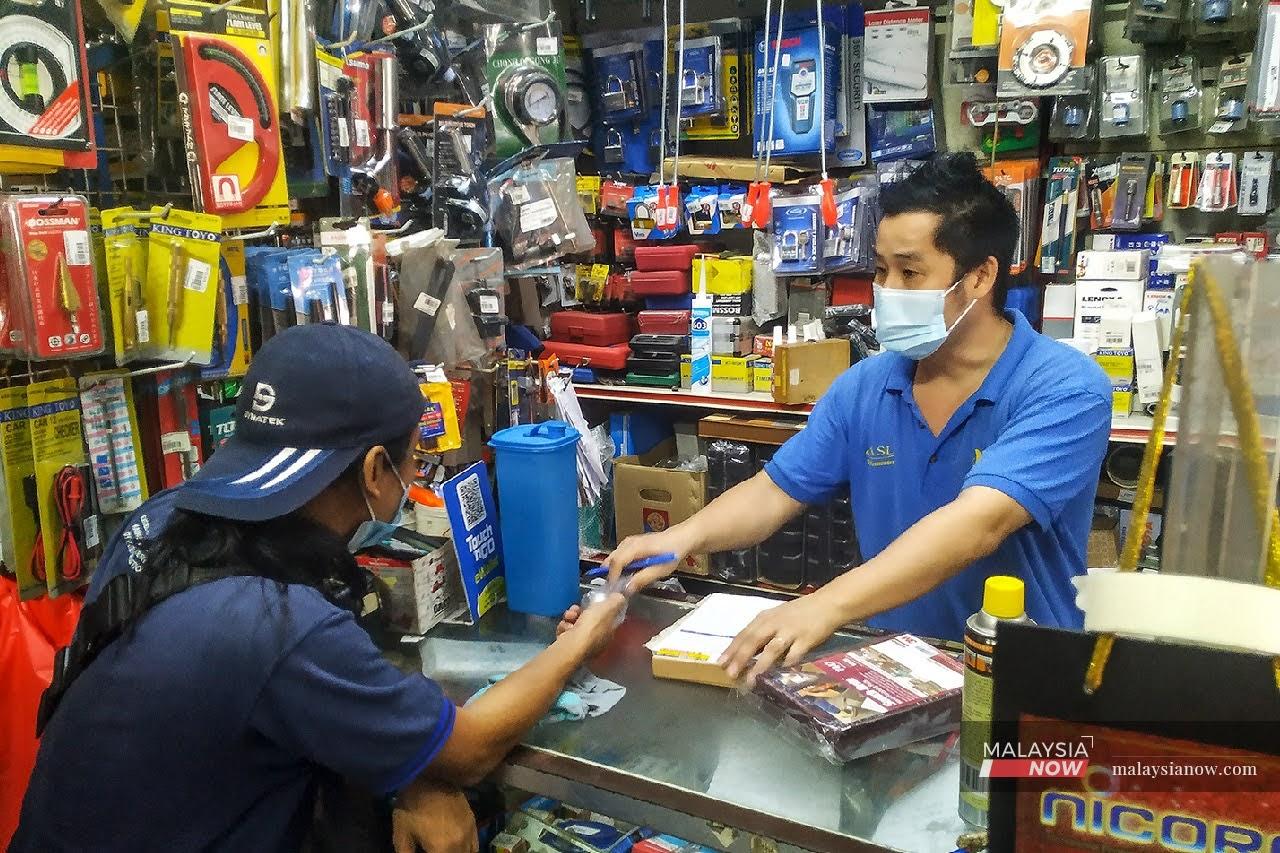 Pemilik kedai perkakasan tradisional, Lee Han Shyang berurusan dengan seorang pelanggan yang hadir ke kedainya di Shah Alam, Selangor.