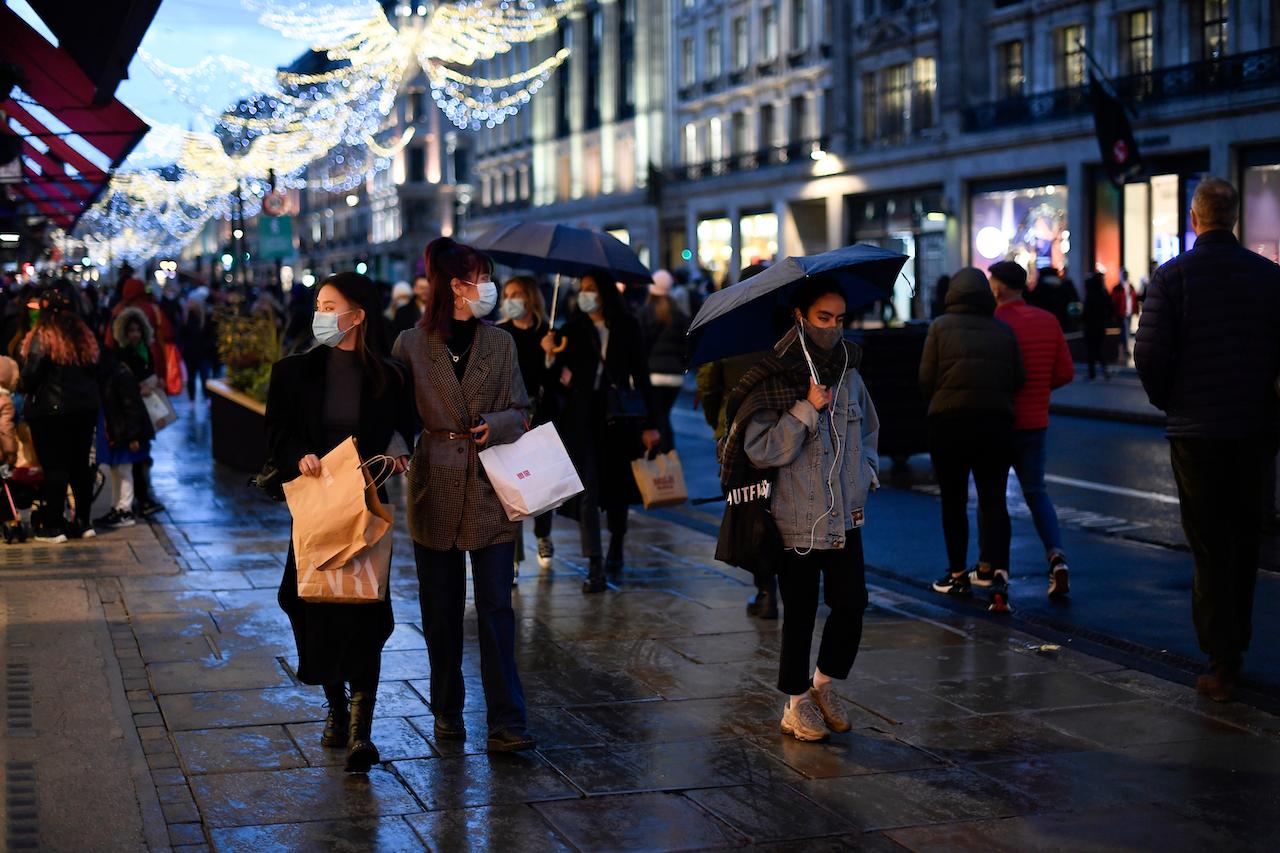 Shoppers wear face masks as they walk in Regent Street, ahead of new restriction measures, in London, Dec 19. Under the new curbs, Christmas gatherings cannot go ahead and non-essential shops must close in London and much of southern England. Photo: AP
