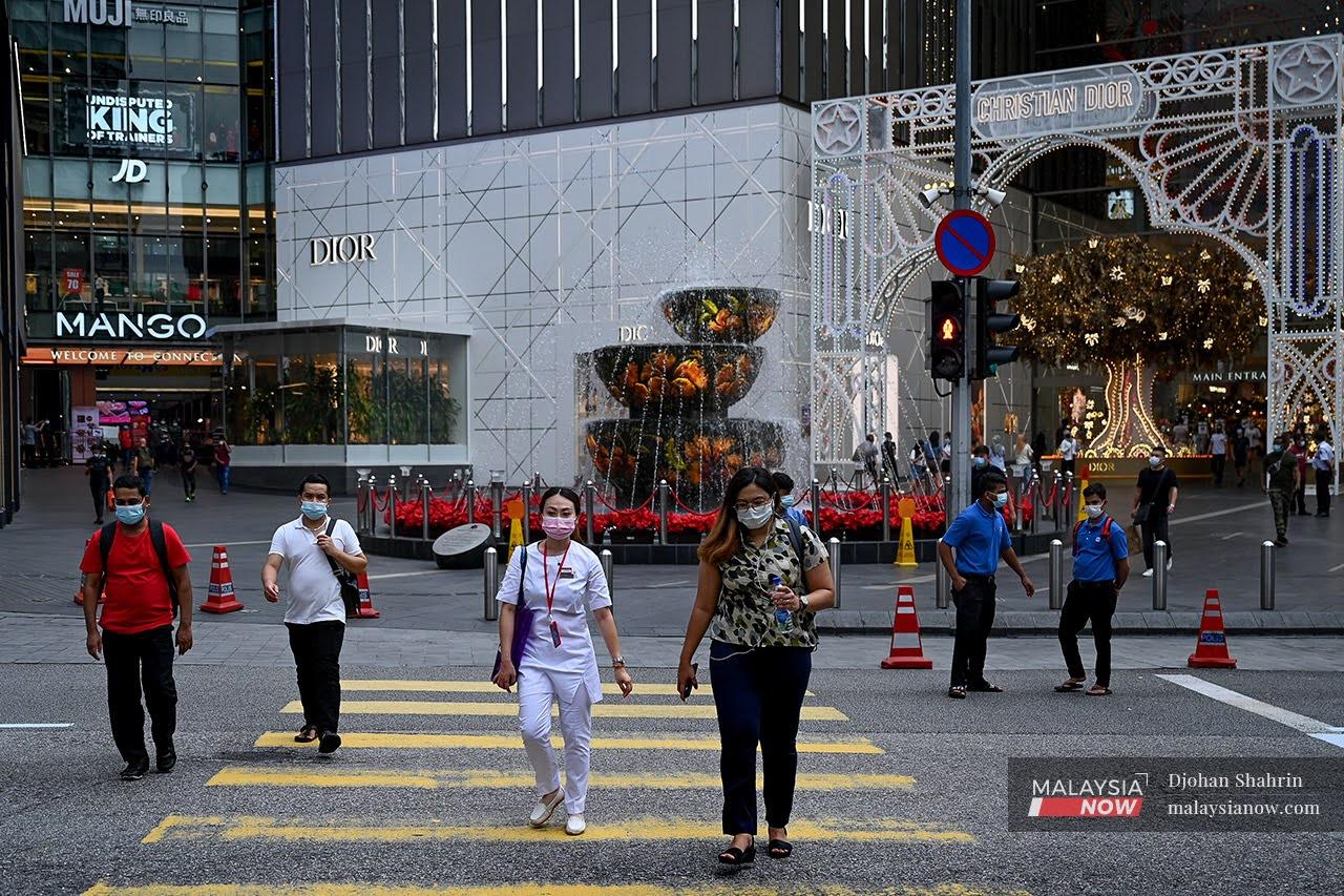 Pedestrians wearing face masks cross the road outside the Pavilion shopping mall in Bukit Bintang, Kuala Lumpur.