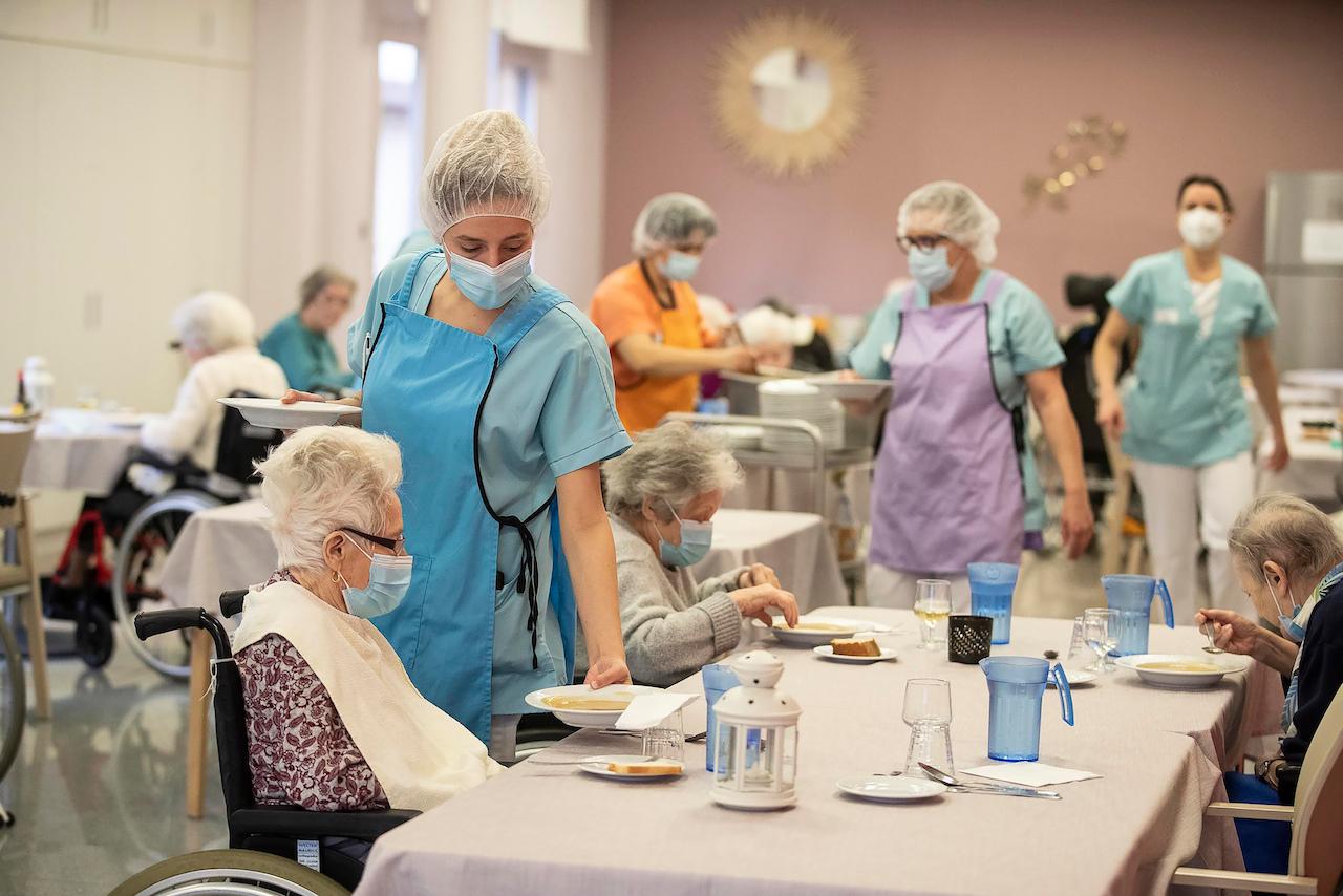 Medical personnel serve food during lunch time at a nursing home in eastern France, Dec 21. Health professionals and other frontliners at high risk of contracting Covid-19 can apply for fast-track naturalisation, the government says. Photo: AP
