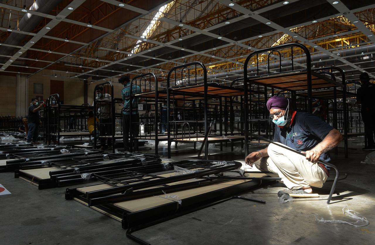 A worker assembles beds in a hall at the MAEPS 2.0 quarantine and low-risk treatment centre in Kuala Lumpur. Photo: Bernama