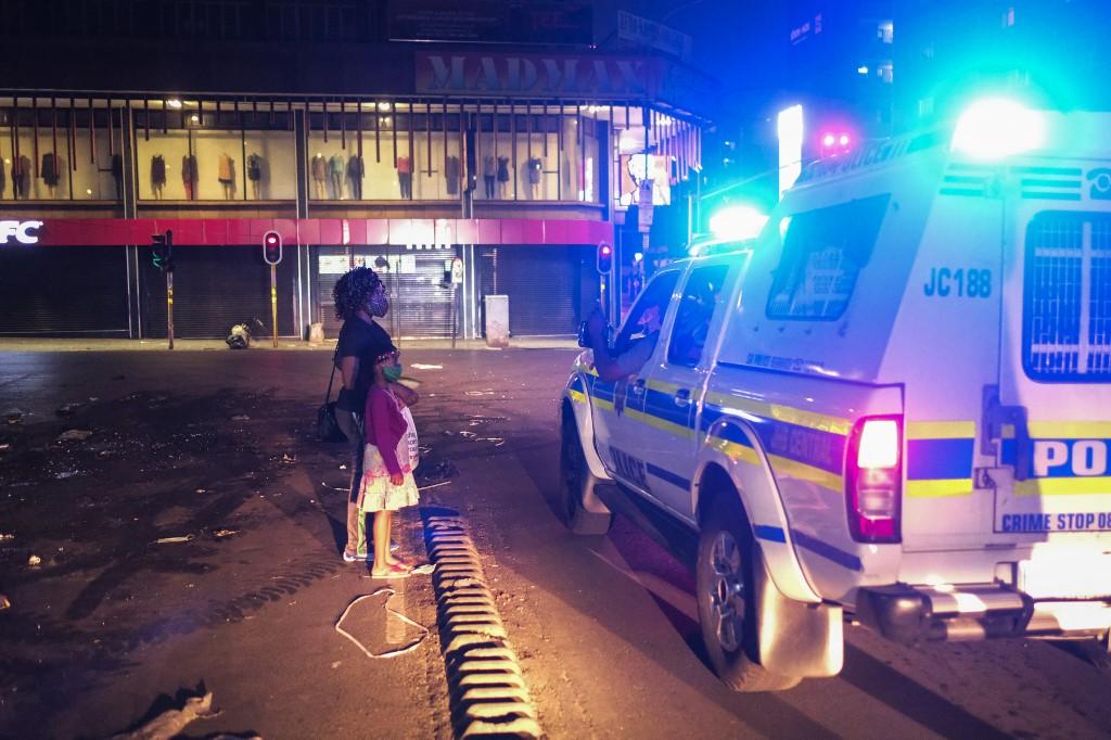 A woman with her child explains to the police why they are still on the street after a new lockdown curfew to help curb the spread of Covid-19 in Johannesburg, South Africa, Dec 29. The president has banned gatherings except for funerals, imposed a night-time curfew and ordered all shops, bars and other venues to shut by 8pm. Photo: AFP