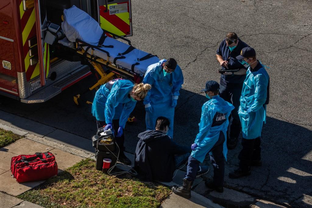 Paramedics examine a potential Covid-19 patient by the side of the road before transporting him to a hospital in Hawthorne, California, Dec 29. Photo: AFP