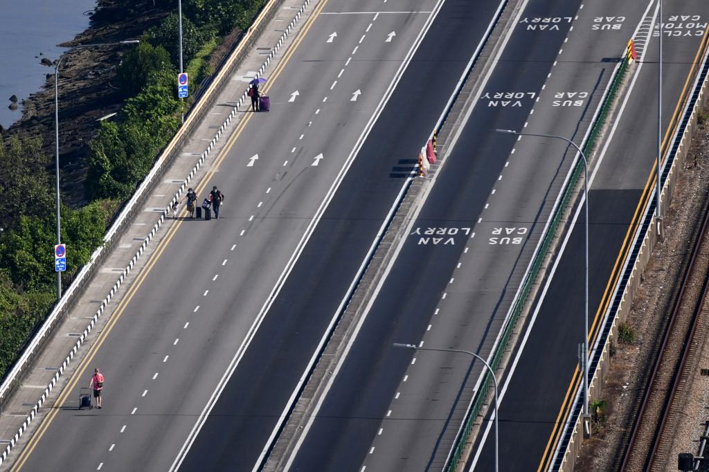 People walk across the causeway linking Johor (top) and Singapore. The Kuala Lumpur-Singapore High Speed Rail project that would have linked the two countries was cancelled today. Photo: AFP
