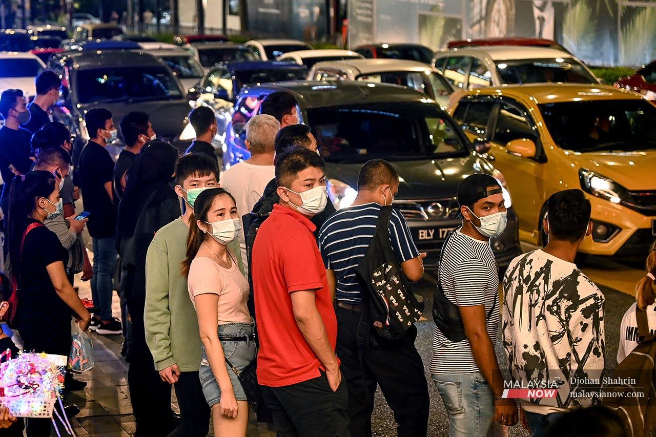People wearing face masks cross a road on New Year's Eve in Bukit Bintang, Kuala Lumpur.