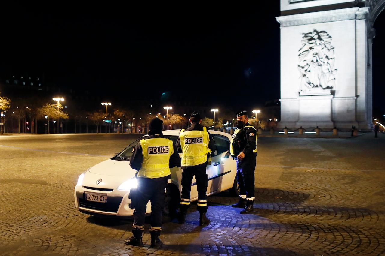 Police check a car on the Champs Elysees avenue on New Year's Eve in Paris. The nationwide curfew of 8pm was not lifted for New Year's. Photo: AP
