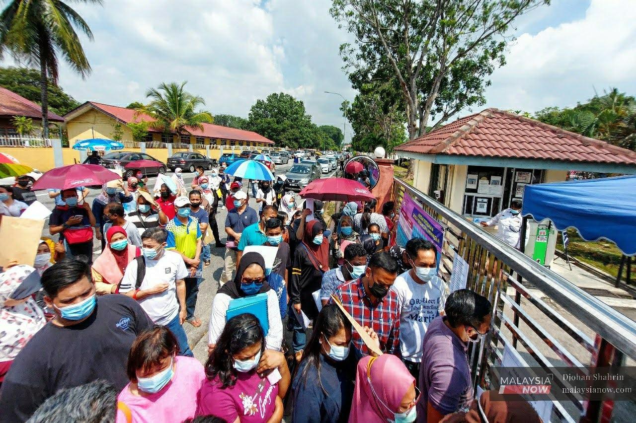 Parents, some of whom had been queuing for hours, wait at the gate outside the Petaling Perdana district education office in Shah Alam on Dec 31.