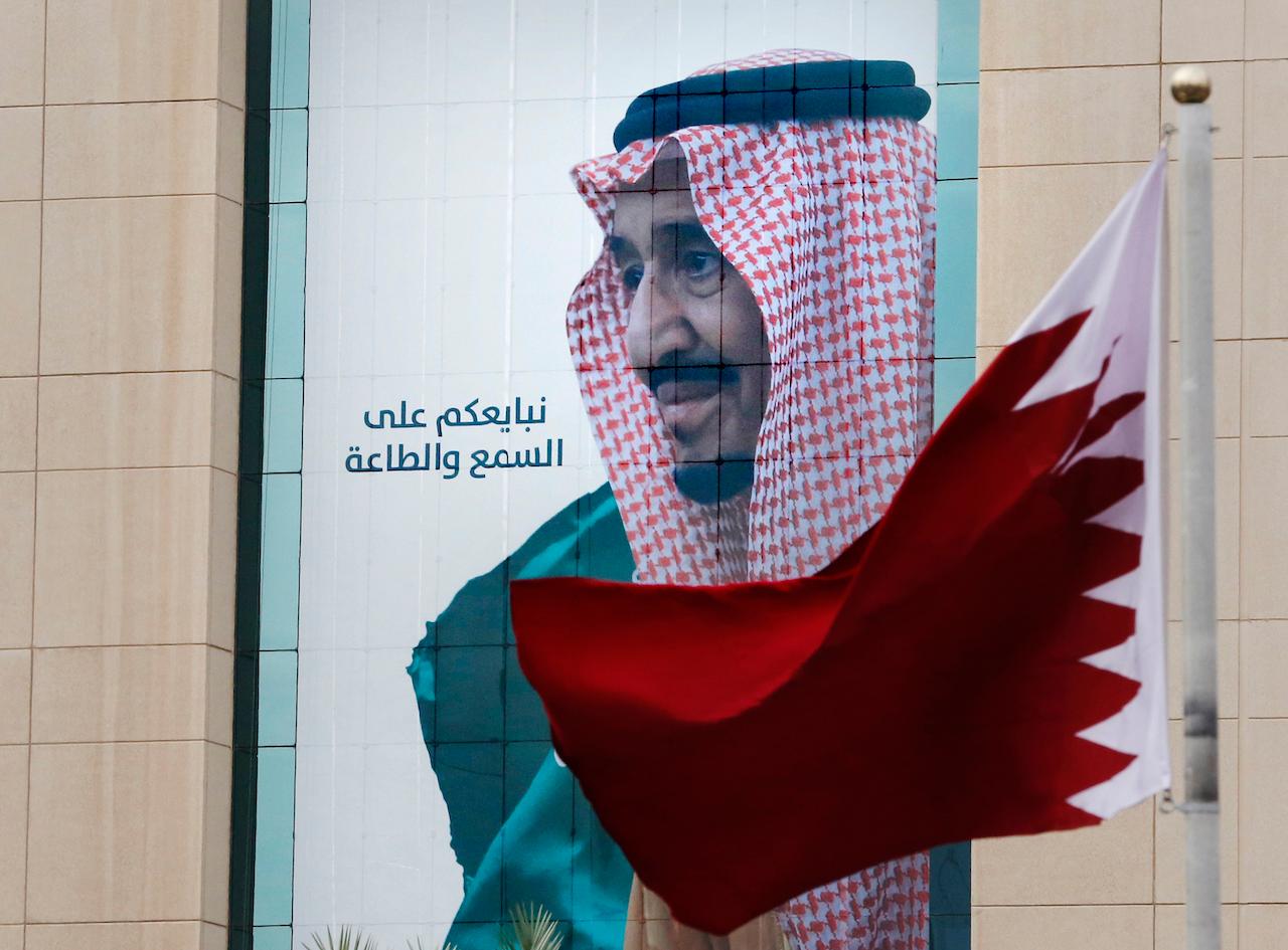In this Dec 9, 2019 file photo, a Qatari flag flies in front of a banner showing Saudi King Salman at a trade centre in Riyadh, Saudi Arabia, ahead of the Gulf Cooperation Council summit. Kuwait's foreign ministry on Jan 4 announced that Saudi Arabia will lift a years-long embargo on Qatar, opening its air and land borders in the first steps toward ending the Gulf crisis. Photo: AP