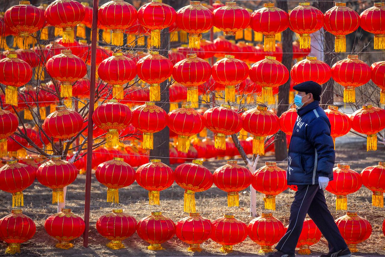 A man wearing a face mask to protect against the spread of the coronavirus walks past a display of lanterns at a public park in Beijing, Jan 5. Photo: AP