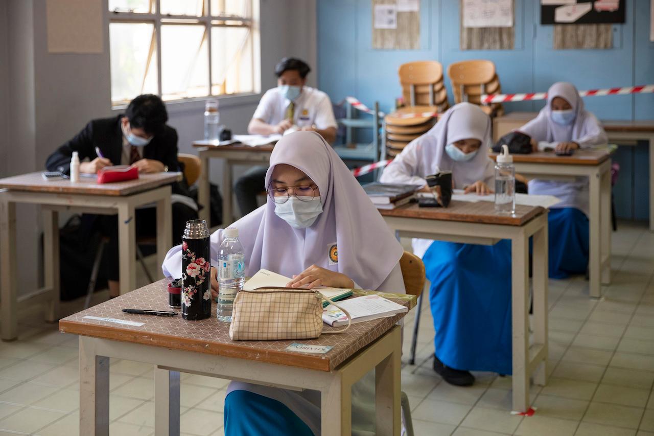 Students wearing face masks maintain social distancing in a classroom at a school in Putrajaya. The Form Three Assessment exam was one of several public examinations scrapped last year following the disruptions to the academic year brought about by the Covid-19 pandemic. Photo: AP