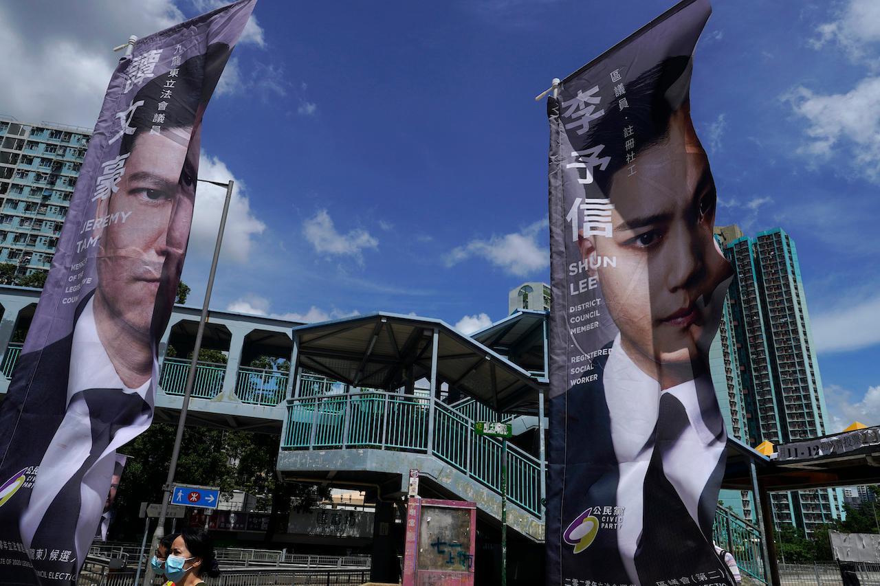 In this July 11, 2020, file photo, a woman walks past banners of pro-democracy candidates outside a subway station in Hong Kong, in an unofficial primary for pro-democracy candidates ahead of legislative elections. About 50 Hong Kong pro-democracy figures were arrested by police on Jan. 6, 2021. Photo: AP