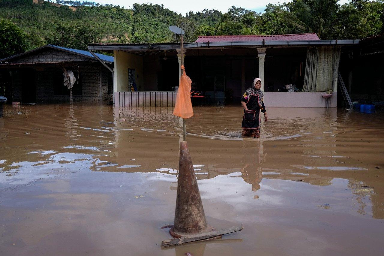 Seorang wanita dilihat meredah banjir yang melanda rumahnya di sekitar kawasan Paya Garok, Jerantut hari ini. Gambar: Bernama