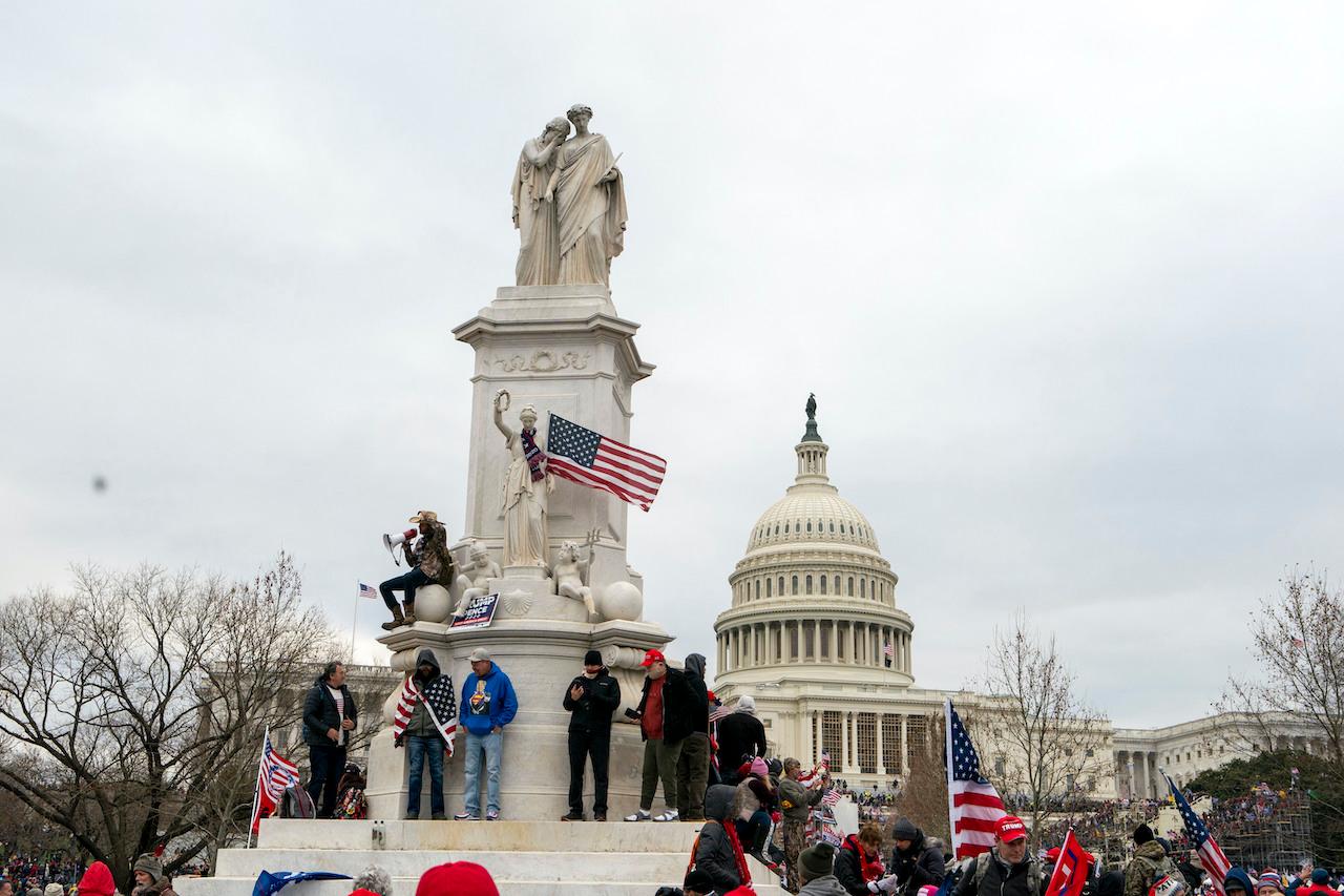 Supporters of President Donald Trump climb the Peace Monument, also known as the Naval Monument or Civil War Sailors Monument, during a rally at the US Capitol on Jan 6, in Washington.