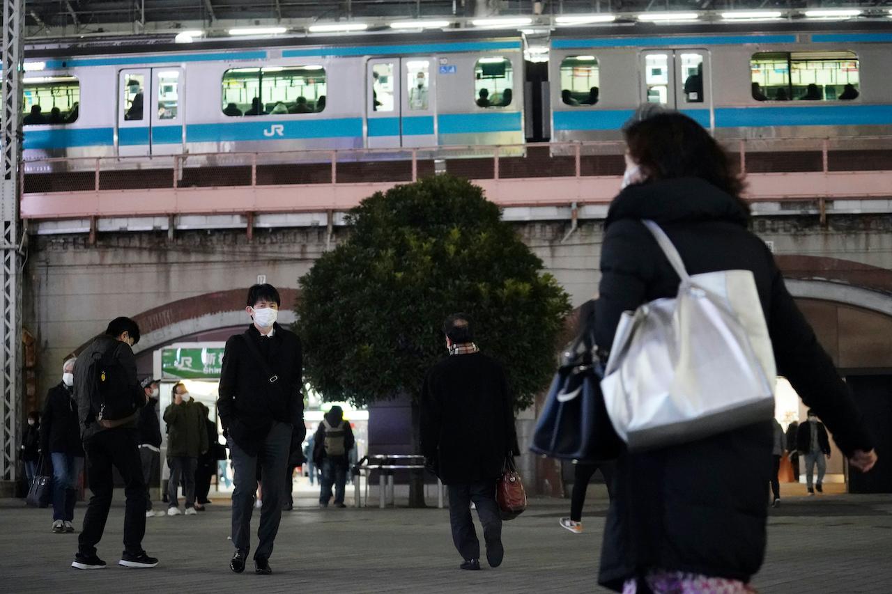 People wearing face masks against the spread of the new coronavirus walk near a train station in Tokyo, Jan 6. Photo: AP