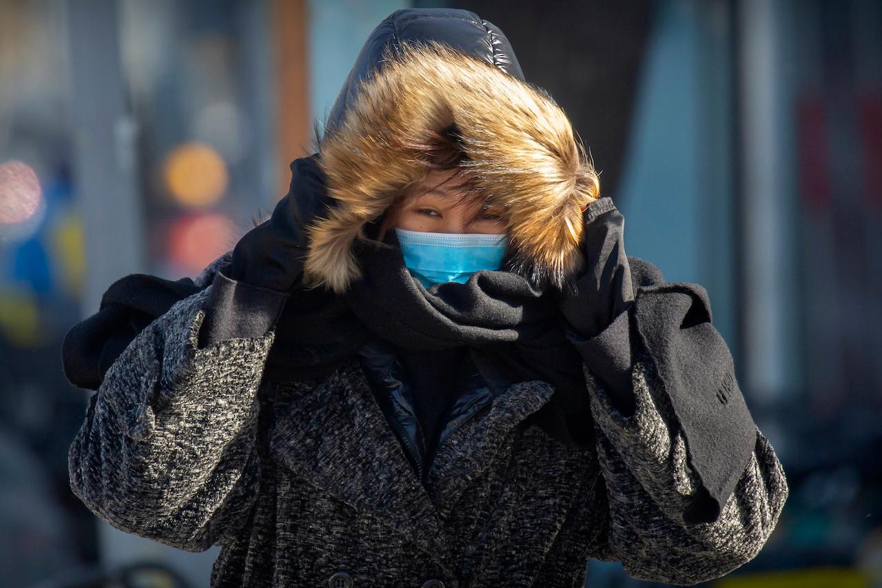 A woman wearing a face mask to protect against the coronavirus walks on an unseasonably cold day at an office and shopping complex in Beijing, Jan 6. Photo: AP
