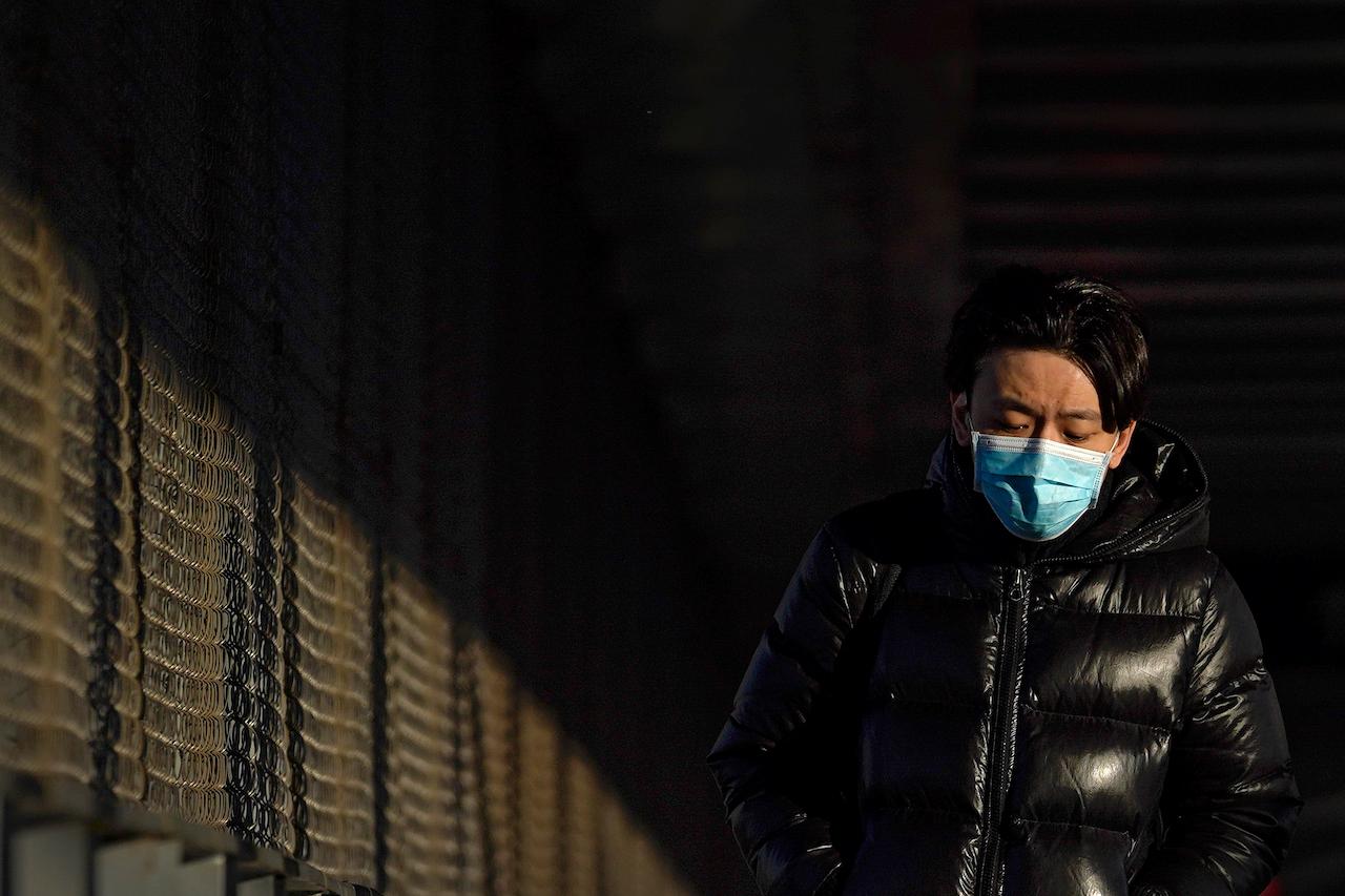 A man wearing a face mask to help curb the spread of the coronavirus walks on a pedestrian bridge in Beijing, Jan 5. China as a whole has reported the biggest rise in daily infections in more than five months. Photo: AP