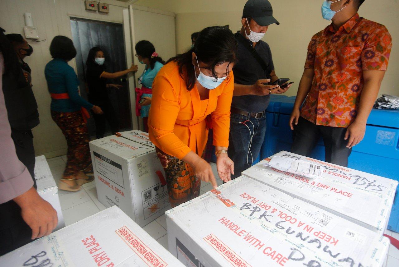 Health workers check boxes containing coronavirus vaccines developed by China's Sinovac Biotech as they arrived in Bali, Indonesia, Jan 7. Photo: AP