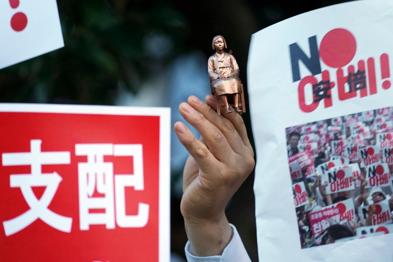A protester holds a miniature model of a statue of a girl symbolising the issue of wartime 'comfort women' during a rally outside the prime minister's residence in Tokyo, Aug 8, 2019. The plight of South Korea's 'comfort women' has been a thorny issue between Seoul and Tokyo for decades. Photo: AP
