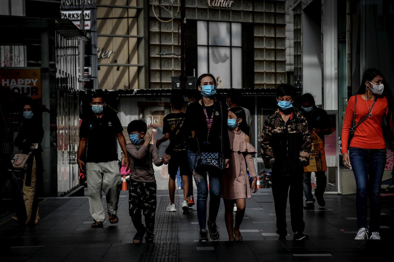 Pedestrians wear face masks as they walk through the streets of Kuala Lumpur. Photo: Bernama