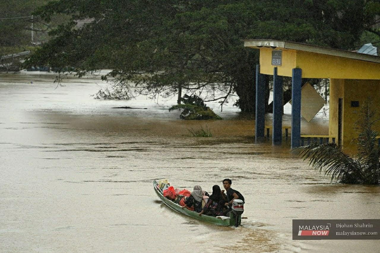 Penduduk Kampung Binjai menggunakan bot untuk keluar dari kawasan banjir di Kuala Lipis, Pahang.