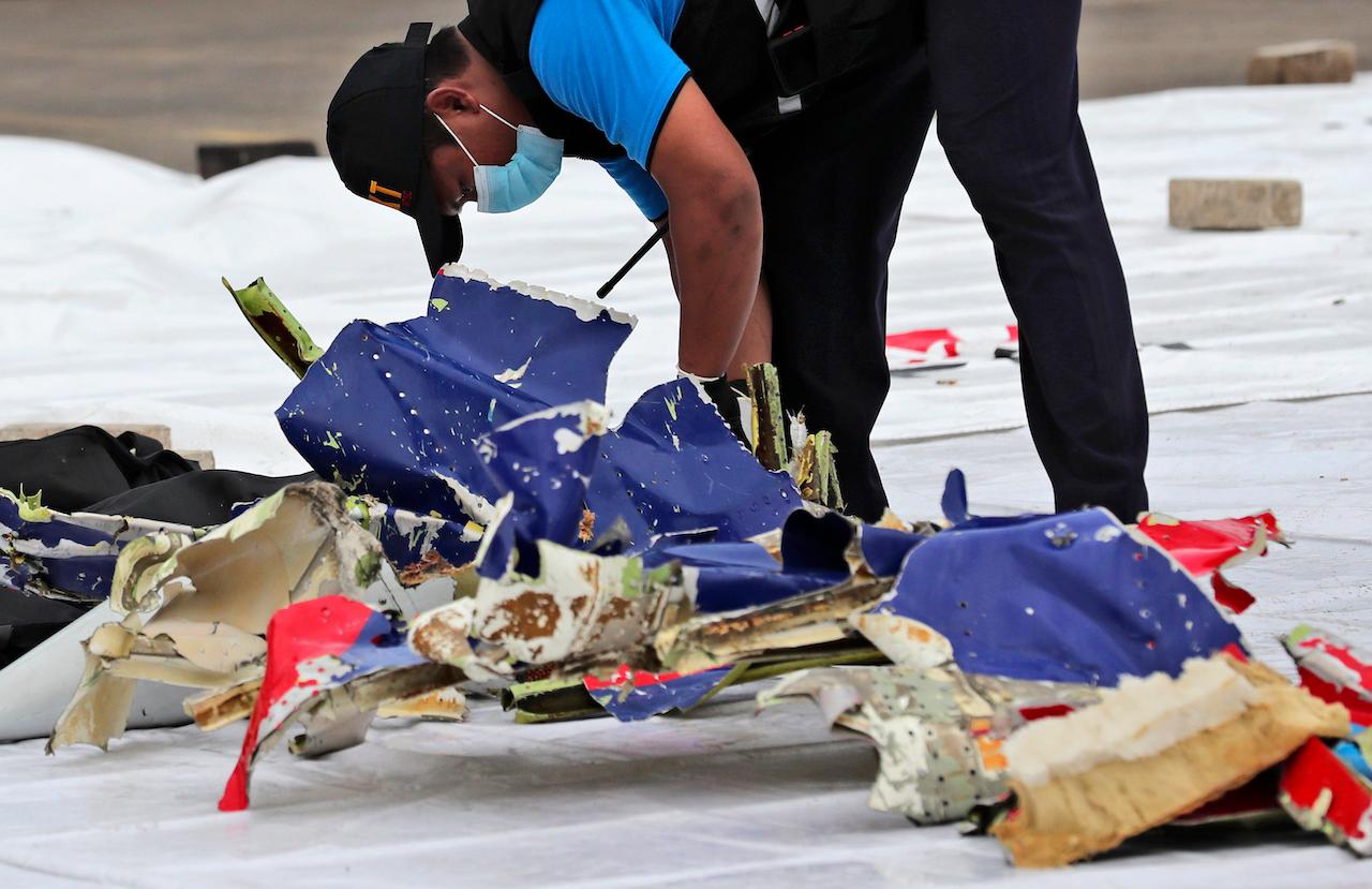 An investigator from the Indonesian National Transportation Safety Committee inspects parts of Sriwijaya Air flight 182 which crashed in the waters off Java Island, at Tanjung Priok Port in Jakarta, Jan 10. Photo: AP