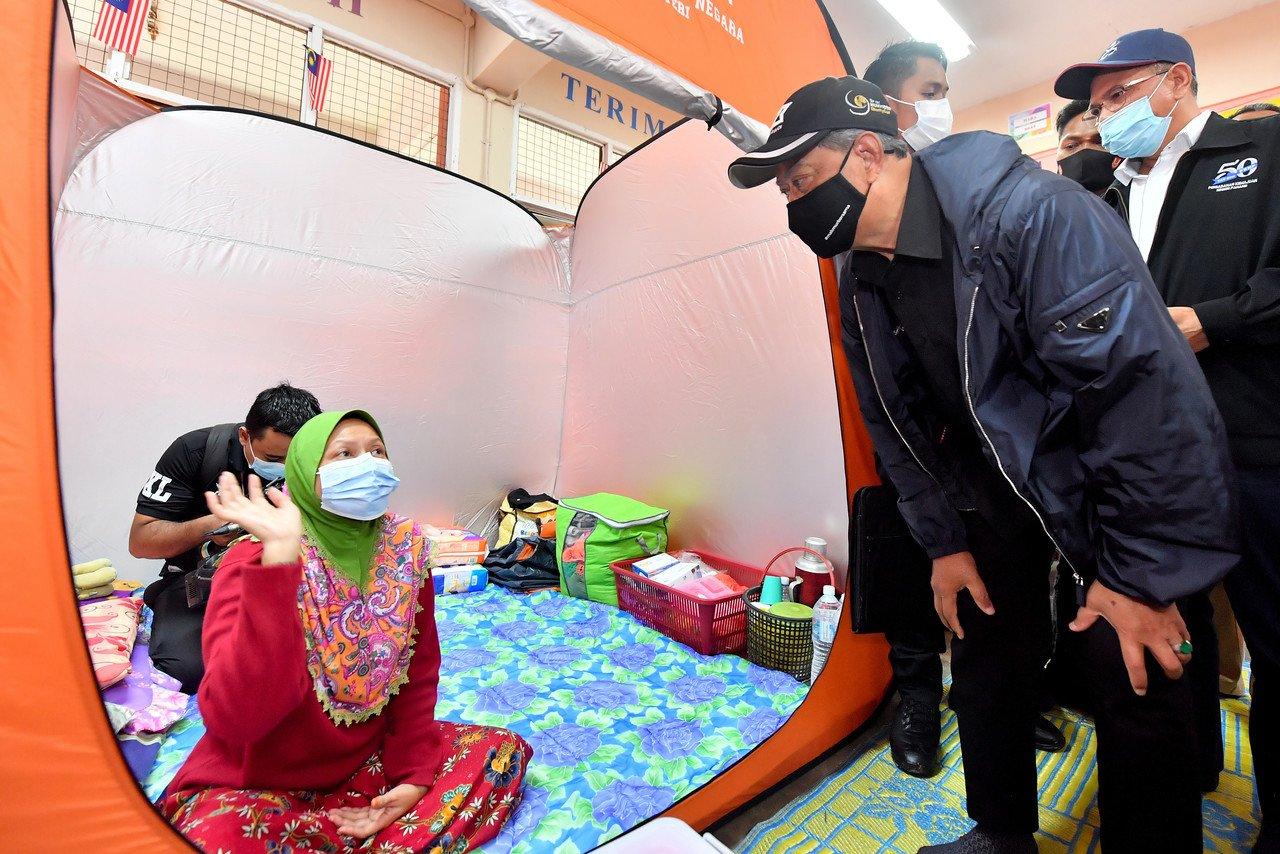 Prime Minister Muhyiddin Yassin meets with flood victims at a temporary relief centre in Temerloh, Jan 10. Muhyiddin is said to be fully occupied with travelling to some of the places worst affected by the seasonal floods, as rumours swirl over the position of DPM. Photo: Bernama