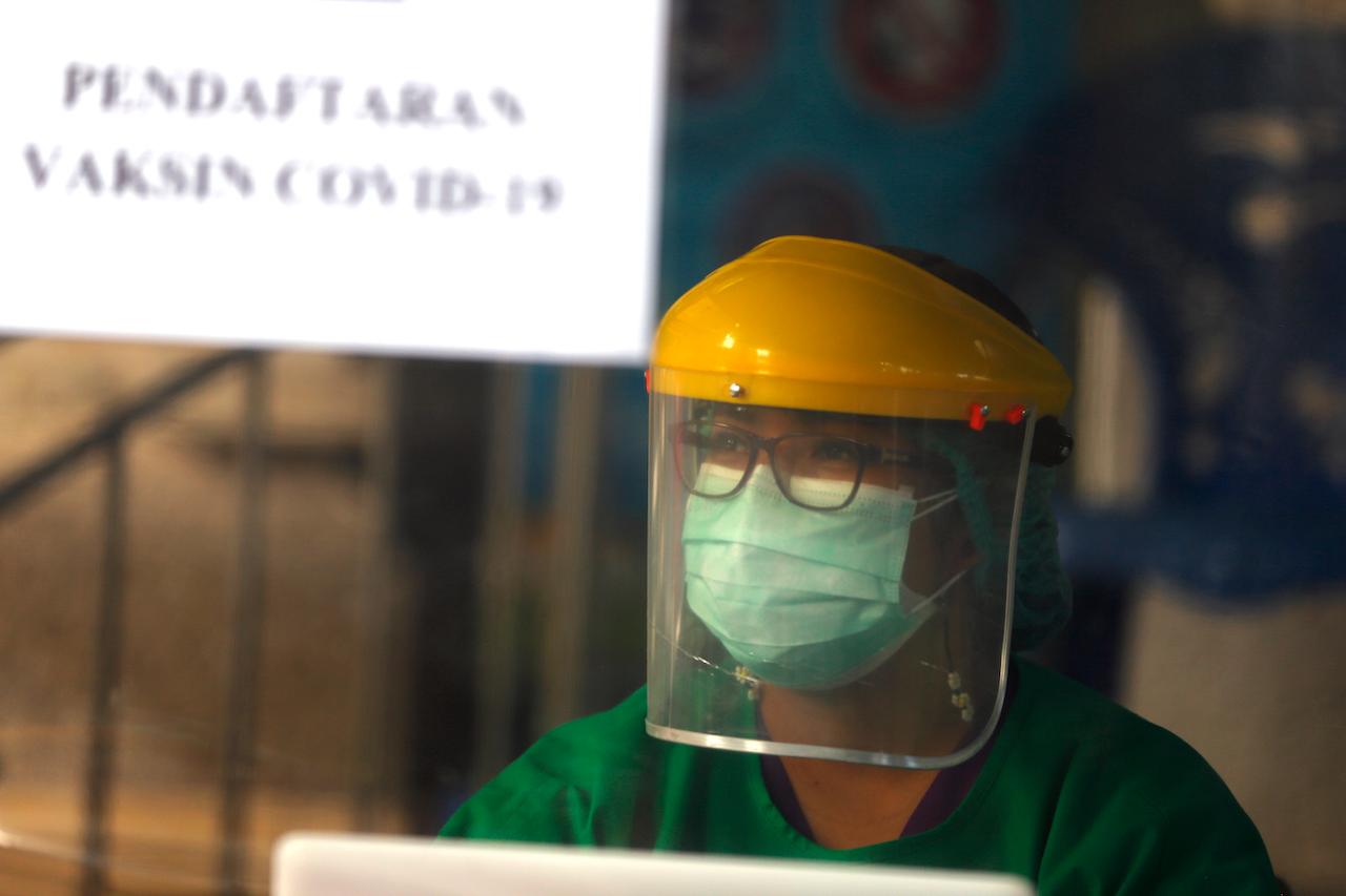 A health worker in a protective suit prepares for a coronavirus vaccine drill in Bali, Indonesia, Jan 11. Photo: AP