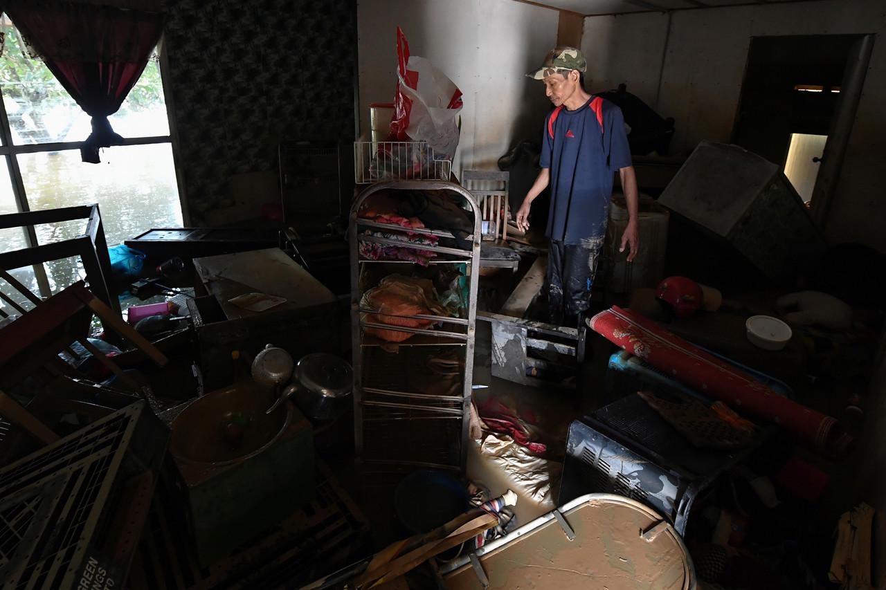Mangsa banjir, Zaharudin Mohammad, 47, melihat barangan dalam rumahnya yang ditenggelami banjir di Kampung Batu 10, Pasir Gajah, Kemaman kelmarin. Gambar: Bernama