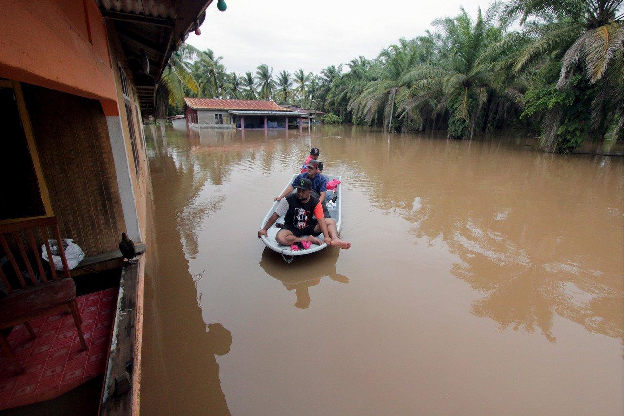 Tiga orang warga Kampung Semangat, Kuantan menaiki bot melakukan rondaan meninjau keadaan rumah penduduk yang ditenggelami banjir hari ini. Gambar: Bernama