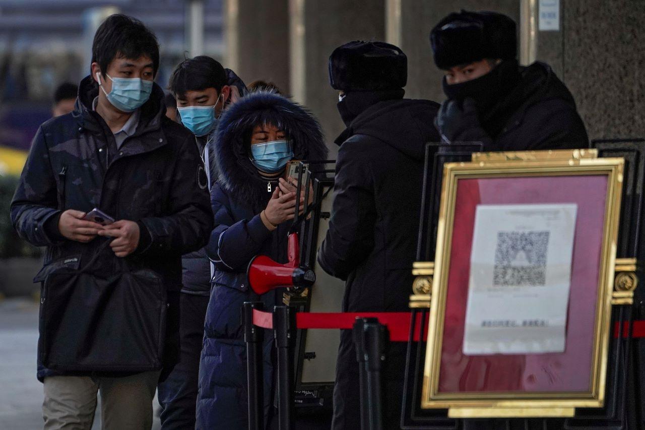 People wearing face masks to help curb the spread of the coronavirus use smartphones to scan their health code before entering an office building in Beijing, Jan 12. Lockdowns have been expanded and a major political conference postponed in a province next to Beijing that is the scene of China's most serious recent Covid-19 outbreak. Photo: AP