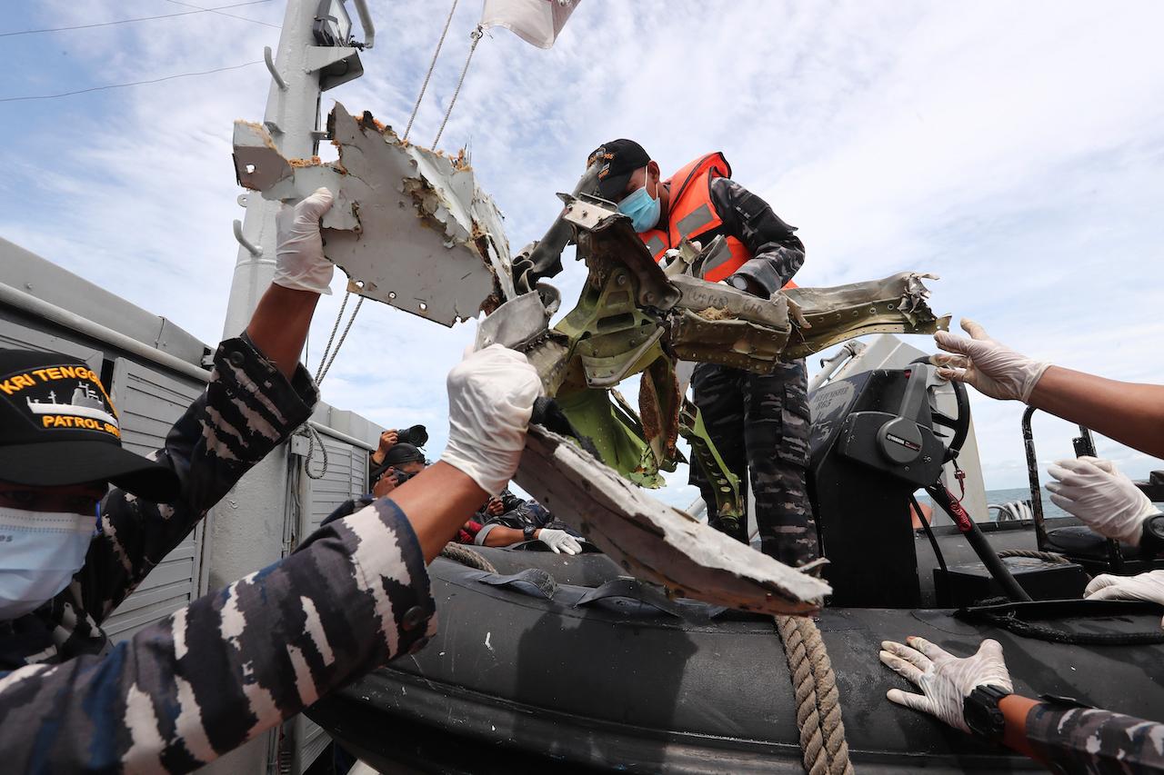 Indonesian navy personnel remove a part of aircraft recovered in the Java Sea where a Sriwijaya Air passenger jet crashed, near Jakarta, Indonesia, Jan 12. Photo: AP