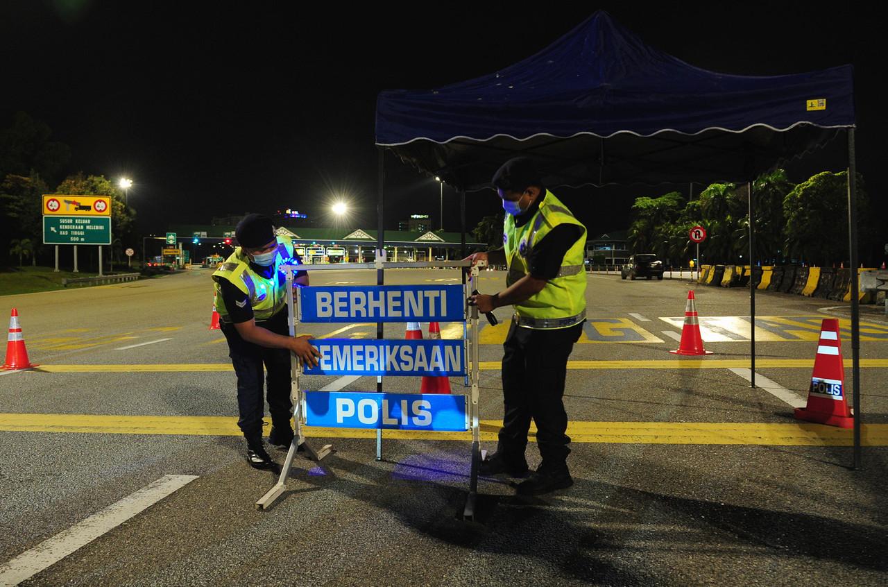 Anggota polis dari Balai Polis Daerah Shah Alam memasang papan tanda berhenti untuk melaksanakan Sekatan Jalan Raya (SJR) ekoran pelaksanaan Perintah Kawalan Pergerakan (PKP) di Plaza Tol Shah Alam tengah malam tadi. Gambar: Bernama