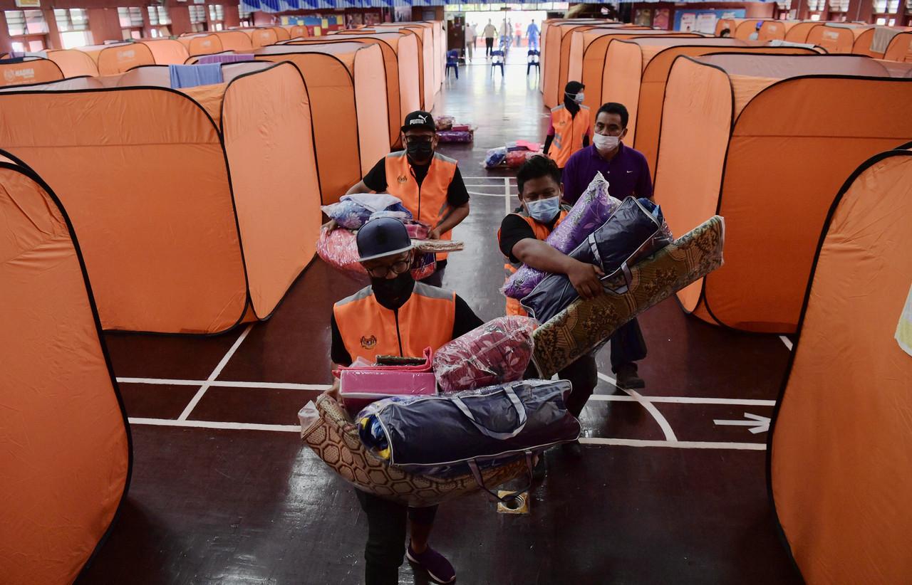 Kakitangan Jabatan Kebajikan Masyarakat Johor mengangkat barang seperti tikar, selimut, bantal dan barang keperluan lain untuk diedarkan kepada mangsa-mangsa banjir yang ditempatkan di Pusat Pemindahan Sementara (PPS) di Dewan Kolej Vokasional Kota Tinggi, Johor pada 5 Januari lalu. Gambar: Bernama