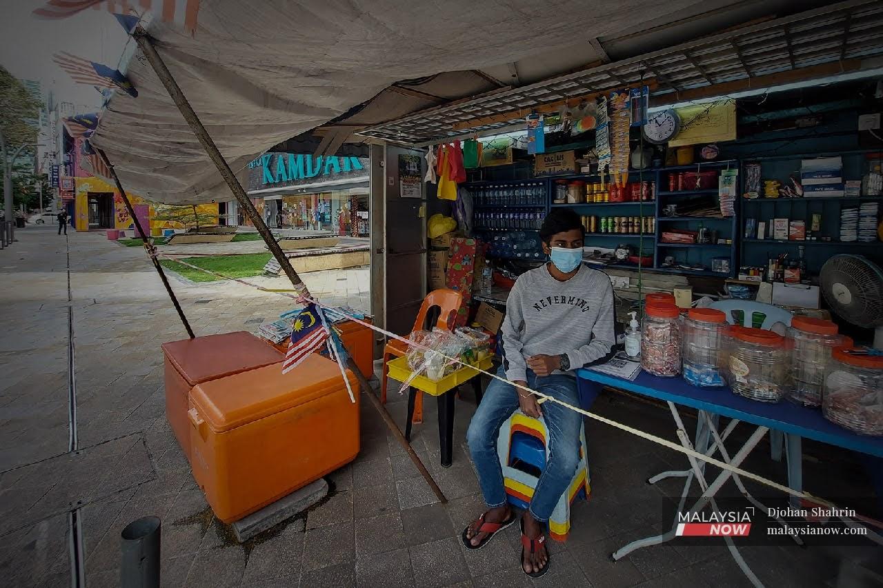 Seorang pekerja Tatcchna Barathy, 21, duduk menunggu pelanggan di kios perniagaan runcit Jalan Tuanku Abdul Rahman. Jalan-jalan sekitar ibu negara kelihatan lengang pada hari pertama Perintah Kawalan Pergerakan (PKP) 2.0.