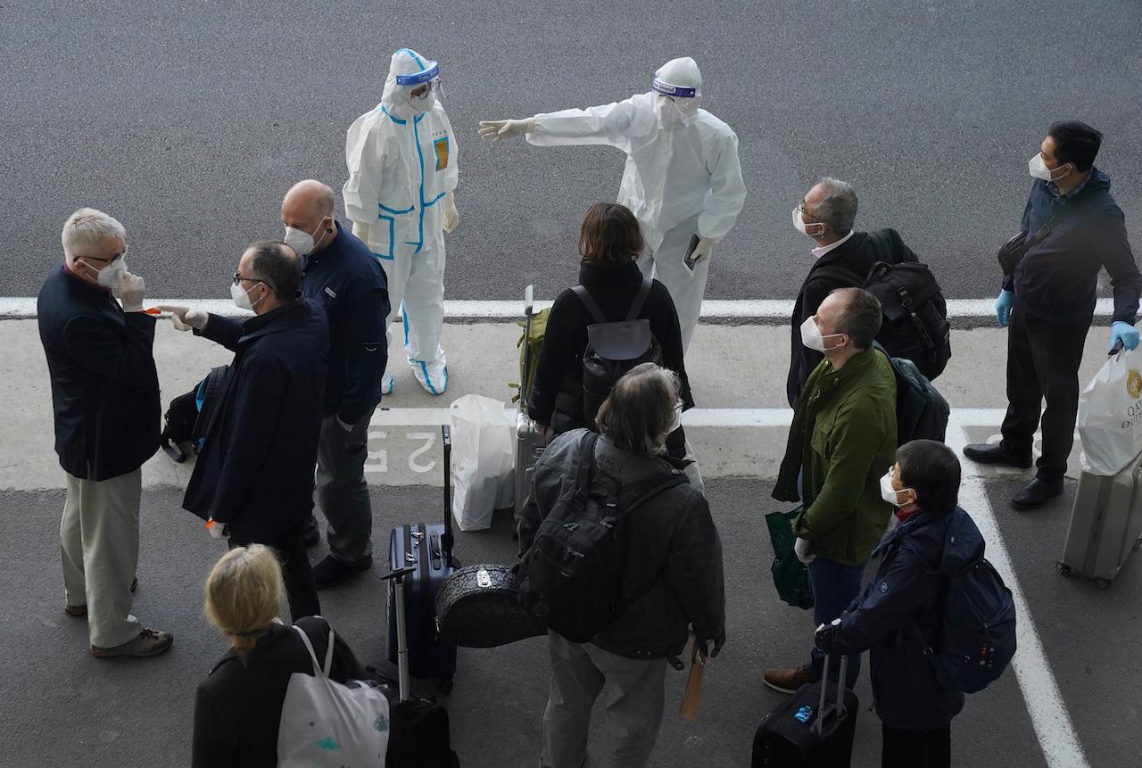 A worker in protective equipment directs members of the World Health Organization team on their arrival at the airport in Wuhan in central China's Hubei province, Jan 14. Photo: AP