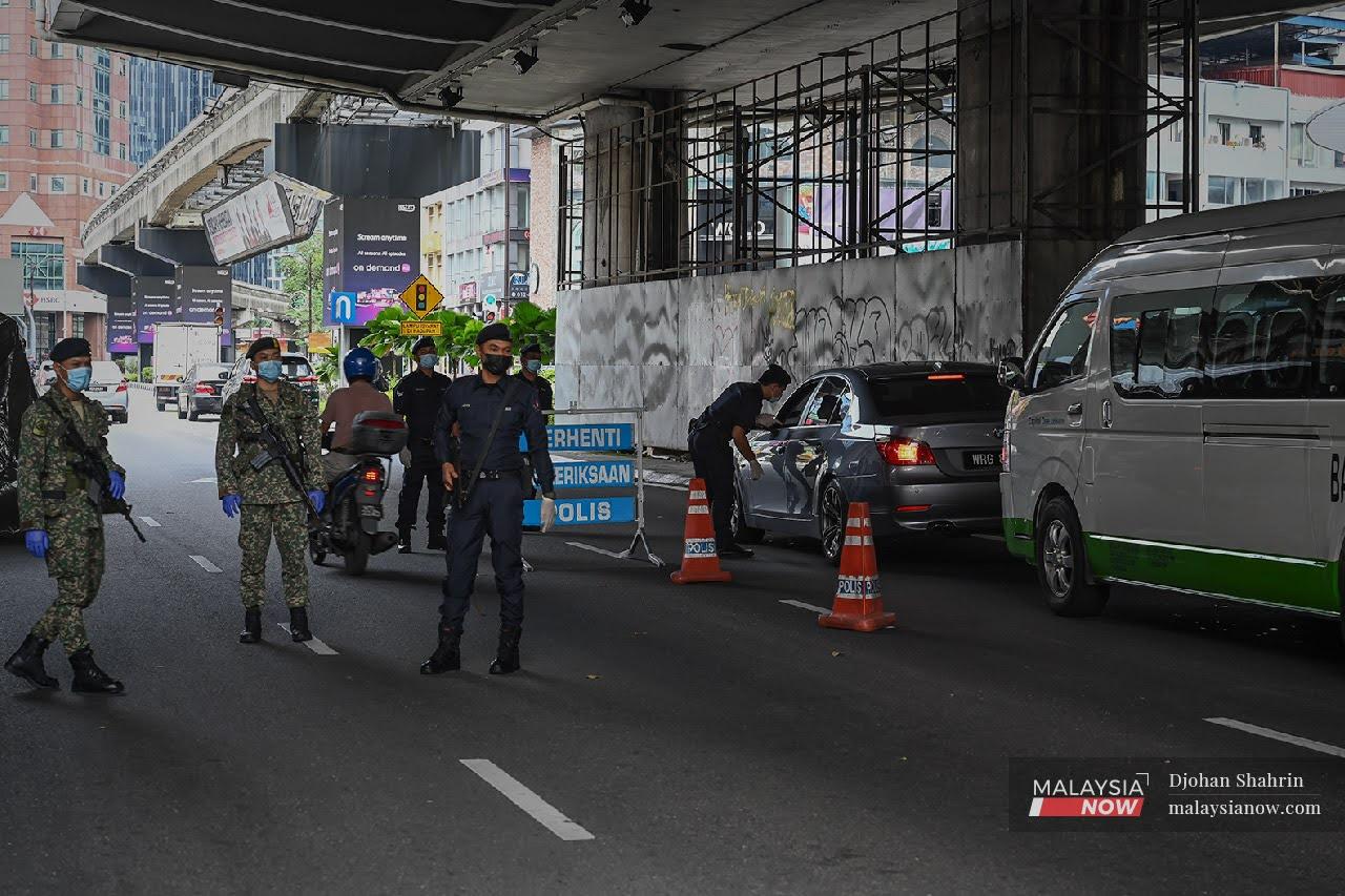 Police officers from the Dang Wangi station monitor a roadblock along with members of the armed forces at Jalan Sultan Ismail in Bukit Bintang, Kuala Lumpur.