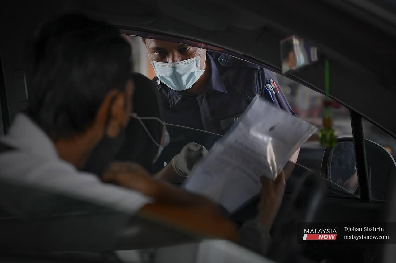Anggota polis dari Balai Dang Wangi melihat surat kebenaran ketika sekatan jalan raya di Jalan Sultan Ismail, Bukit Bintang.