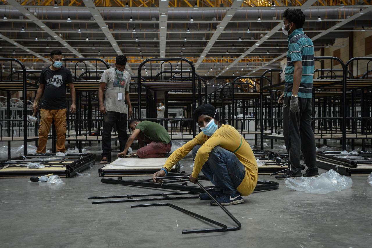 Kelihatan para pekerja sedang memasang katil pesakit di dalam sebuah dewan di Pusat Kuarantin dan Rawatan Berisiko Rendah (PKRC) Taman Ekspo Pertanian Malaysia Serdang (Maeps). Gambar: Bernama