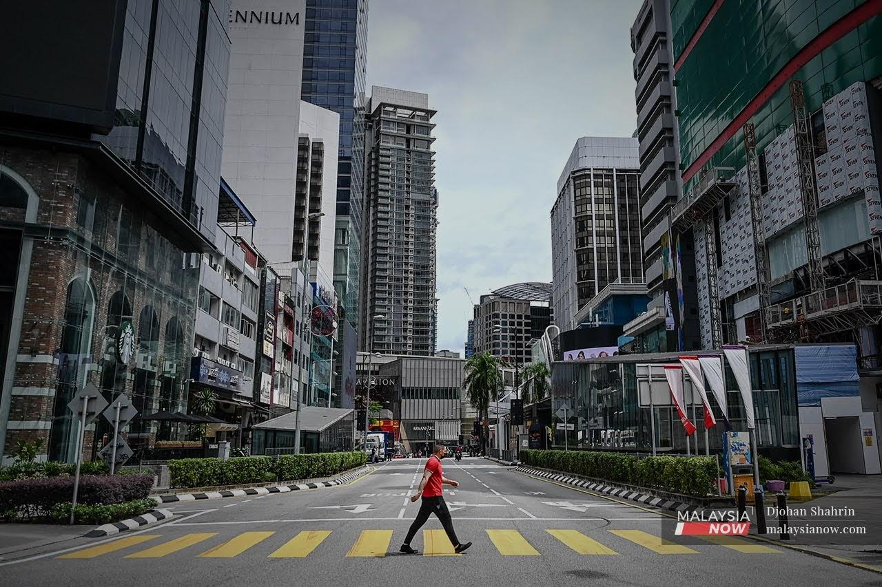 Seorang pejalan kaki melintas jalan di Jalan Bukit Bintang, Kuala Lumpur yang lengang selepas pelaksanaan Perintah Kawalan Pergerakan 2.0.