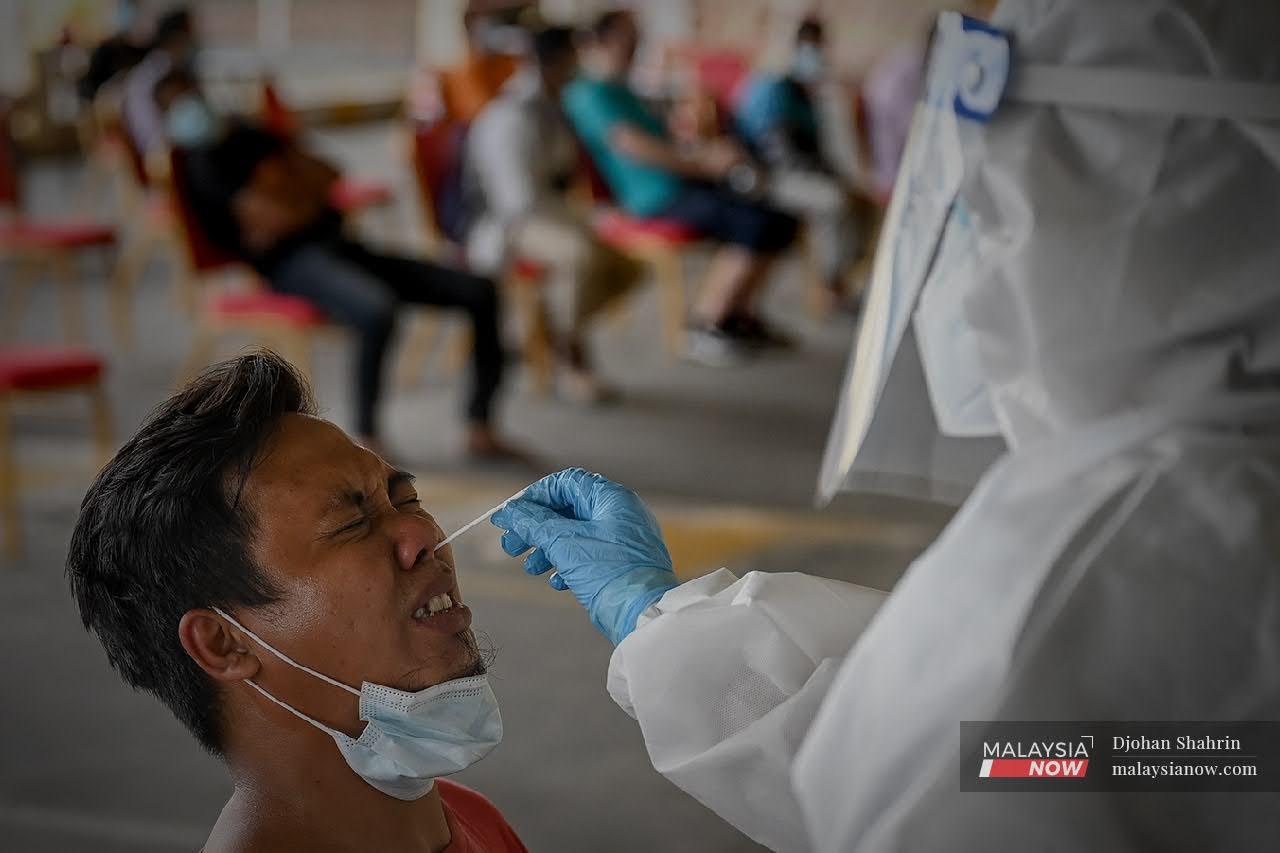 A health worker takes a swab sample during a Covid-19 screening in Cheras, Kuala Lumpur. Cases have been spiking in several areas in Negeri Sembilan, which will be placed under movement control order from tomorrow onwards.