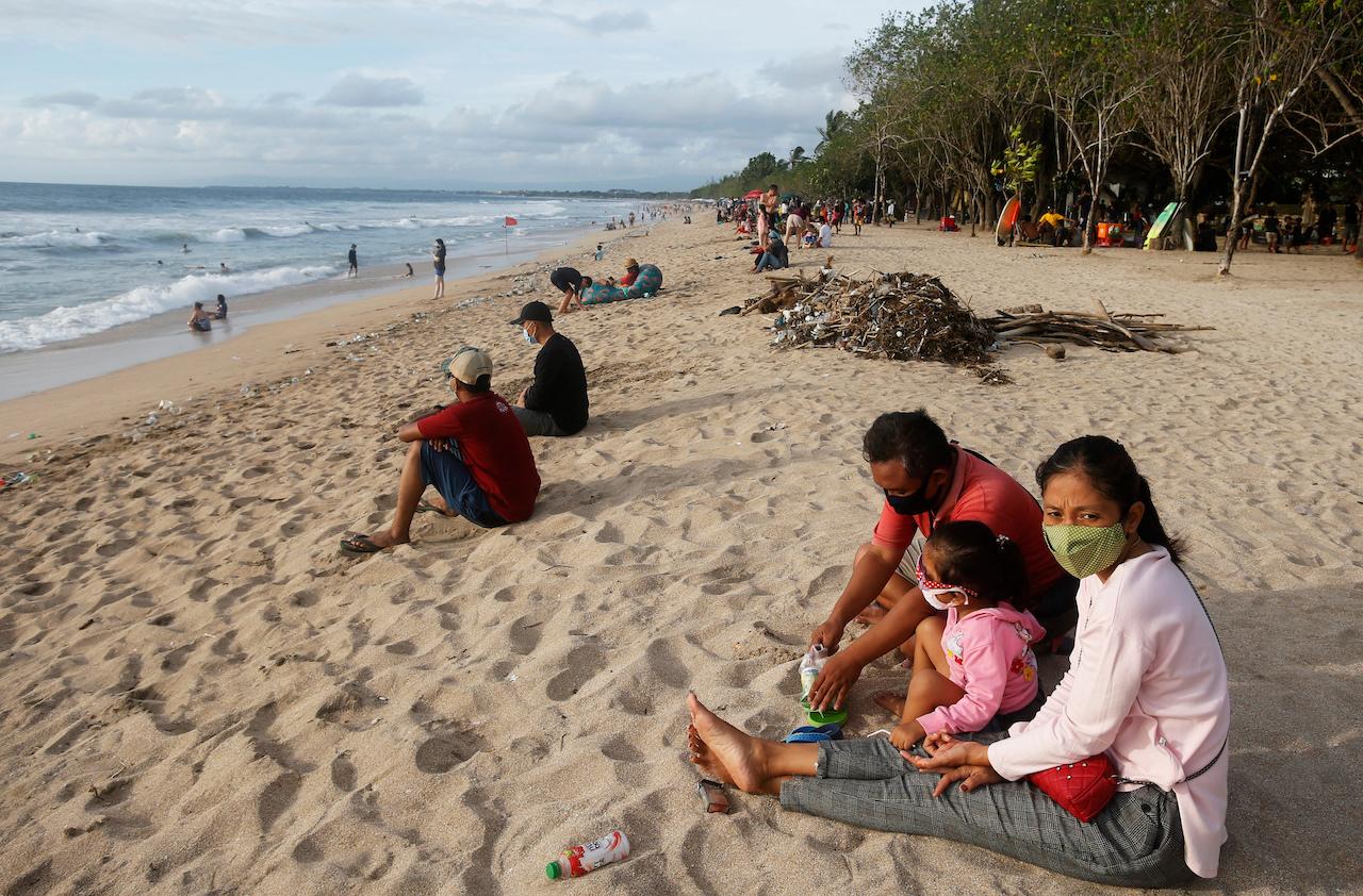Family members wearing masks to help curb the spread of the coronavirus sit apart from other people to maintain physical distance at a beach in Bali, Indonesia, Dec 22, 2020. Photo: AP