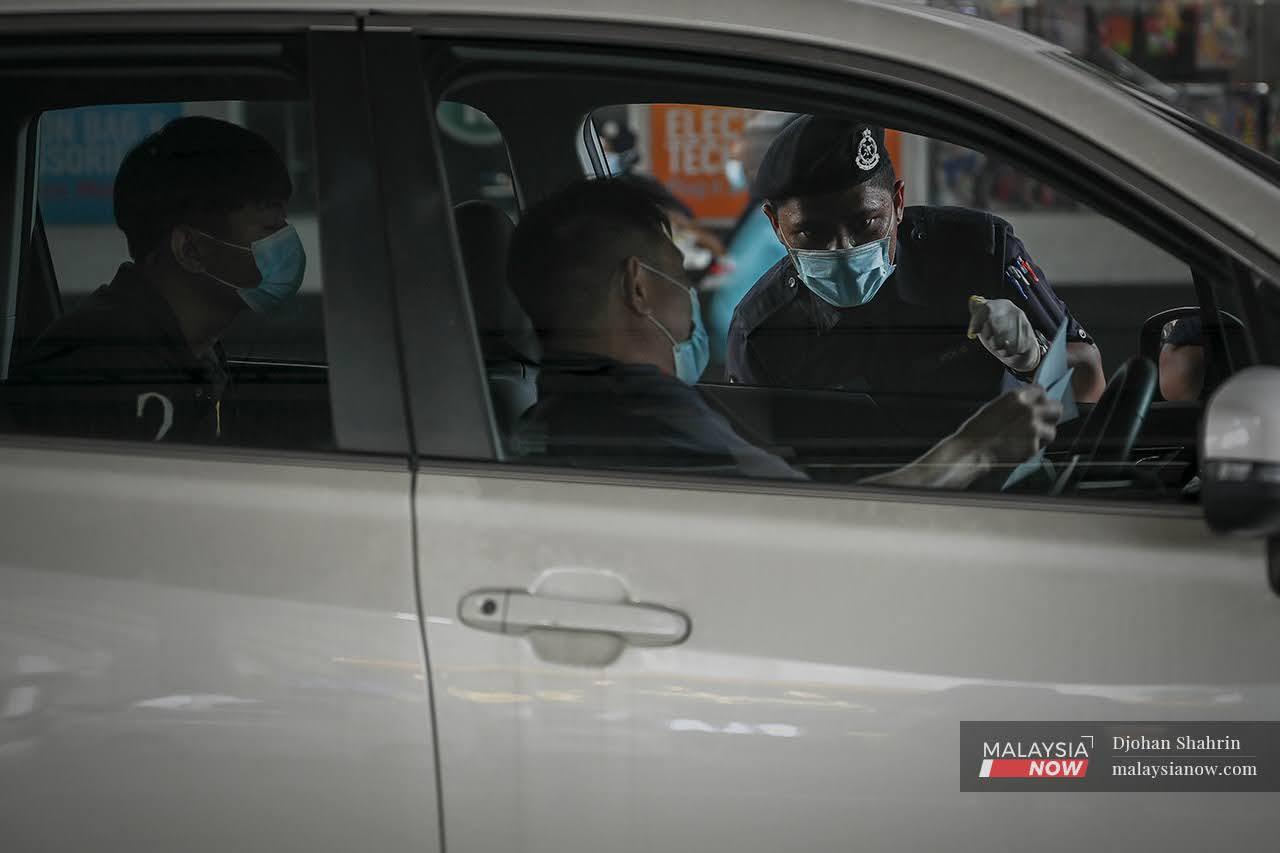 Police from the Dang Wangi station in Kuala Lumpur question a driver at a roadblock in Jalan Sultan Ismail, Bukit Bintang.