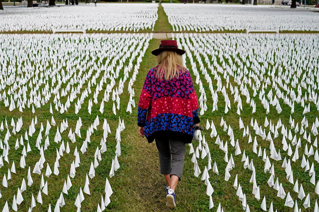 A woman walks among thousands of white flags planted in remembrance of Americans who have died of Covid-19 near the Robert F Kennedy Memorial Stadium in Washington. Photo: AP