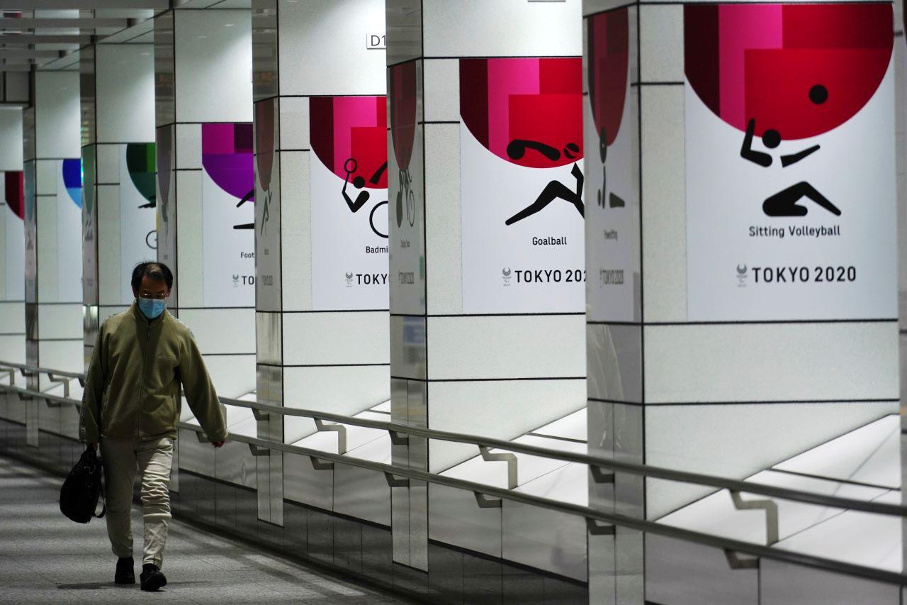 A man wearing a protective mask to help curb the spread of the coronavirus walks near banners of the Tokyo 2020 Olympics and Paralympics in Tokyo, Jan 19. Photo: AP