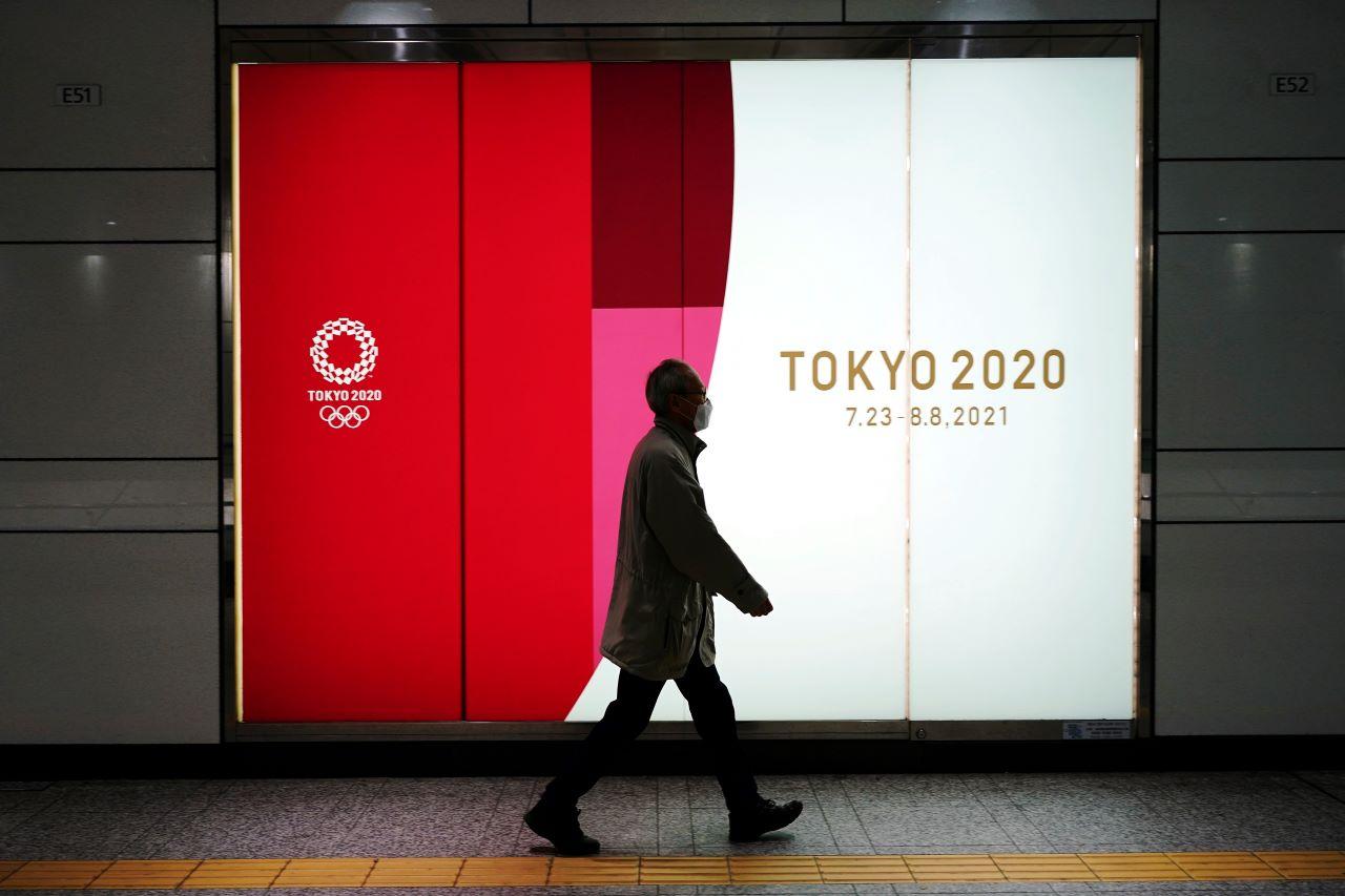 A man wearing a protective mask to help curb the spread of the coronavirus walks near a banner of the Tokyo 2020 Olympics at an underpass in Tokyo, Jan 19. Photo: AP