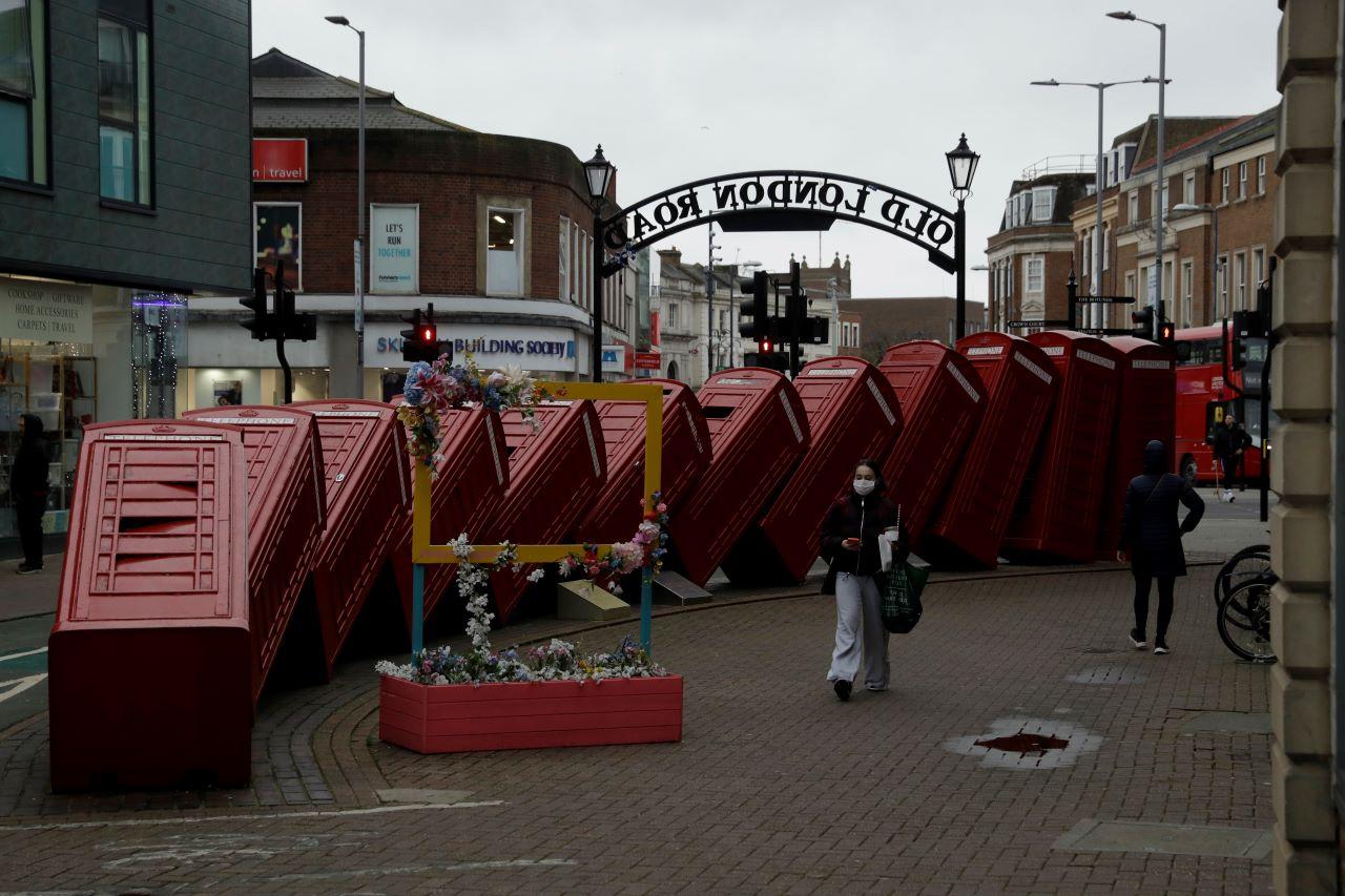 A woman wearing a face mask to curb the spread of coronavirus walks past a sculpture of phone boxes in southwest London, Jan 19, during England's third national lockdown since the coronavirus outbreak began. Photo: AP