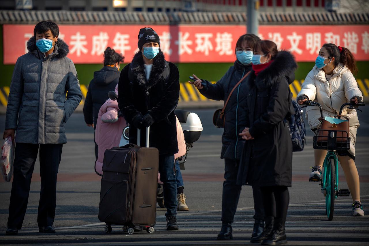People wearing face masks to protect against the spread of the coronavirus wait to cross an intersection in Beijing, Jan 20. Photo: AP